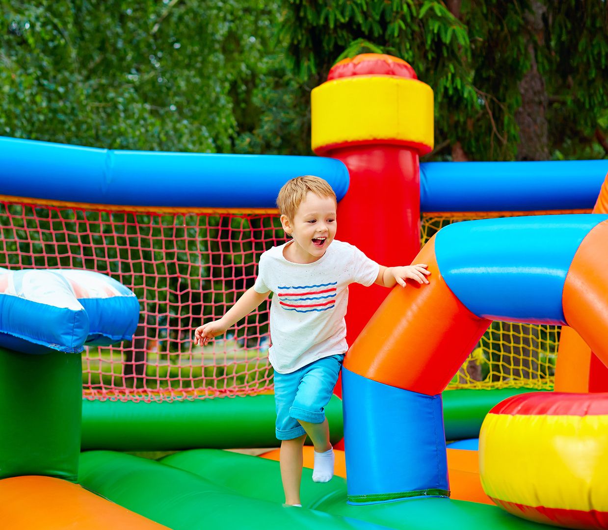 Ein junger Junge springt fröhlich auf einem aufblasbaren Hüpfburg und genießt das Spiel im Freien.